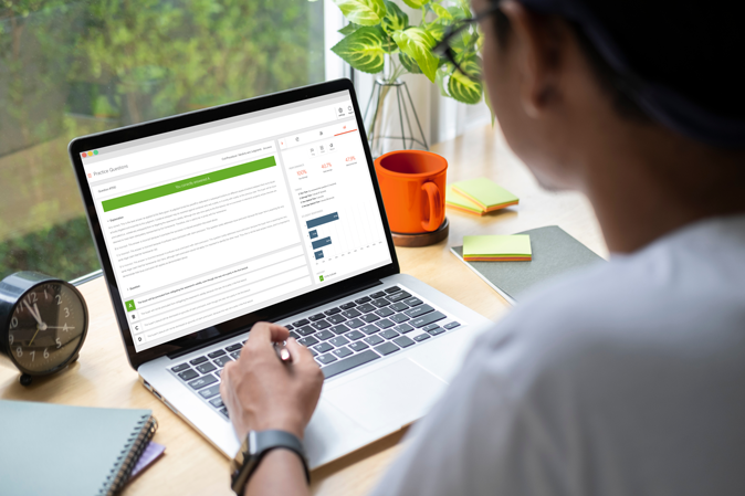 Person sitting at a desk on a laptop showing the MCQ Simulator