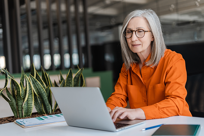 Older woman sitting at a desk working on a laptop