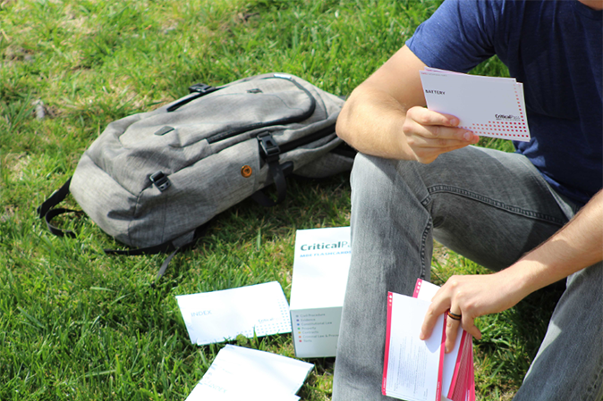 Young man sitting on the grass with his backpack using the CriticalPass cards