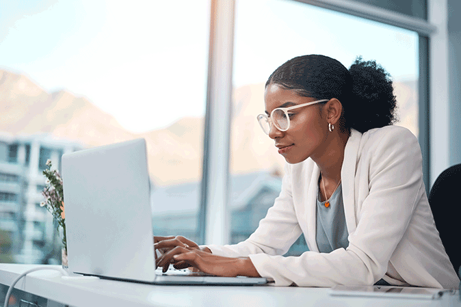 Young woman dressed professionally typing on a laptop in an office
