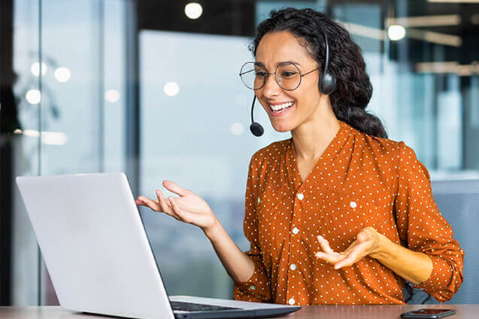 Young woman wearing a headset while talking to someone on a laptop